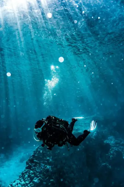 A scuba diver exploring a sunlit coral reef